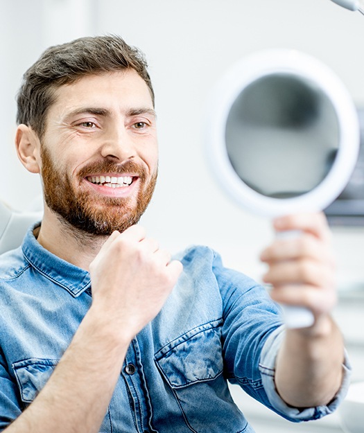 Man looking at smile in mirror after dental treatment
