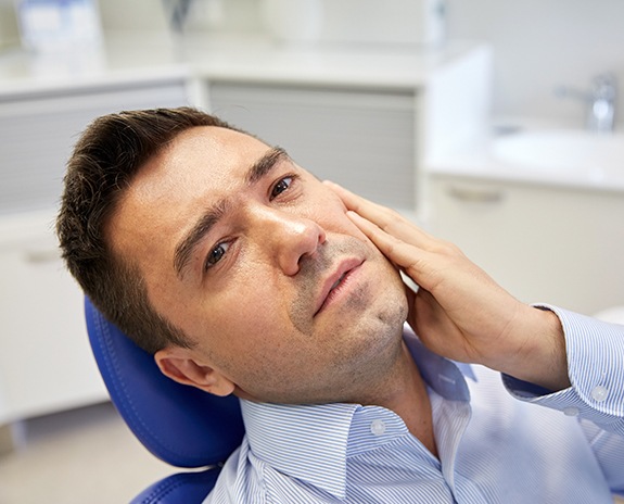 Man in need of root canal therapy holding cheek in pain