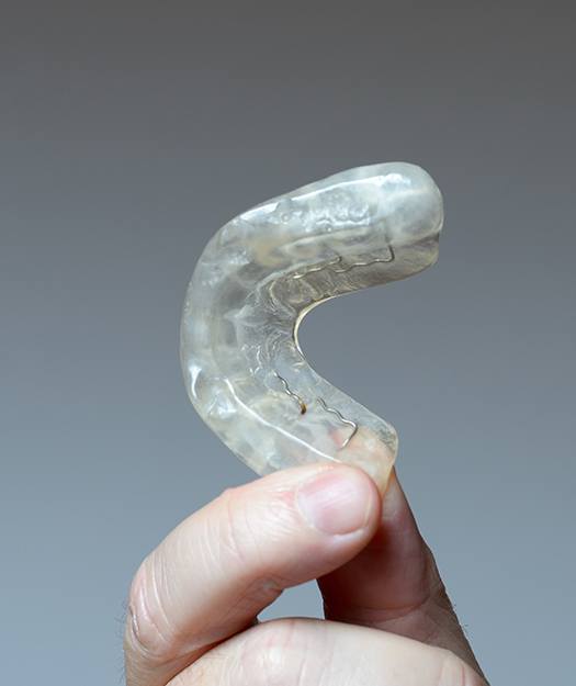 Hand holding up an oral appliance