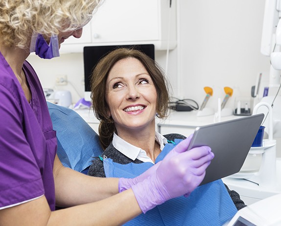 Woman in dental chair smiling at dnetal team member