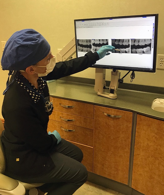 Dentist pointing to area on digital dental x-rays