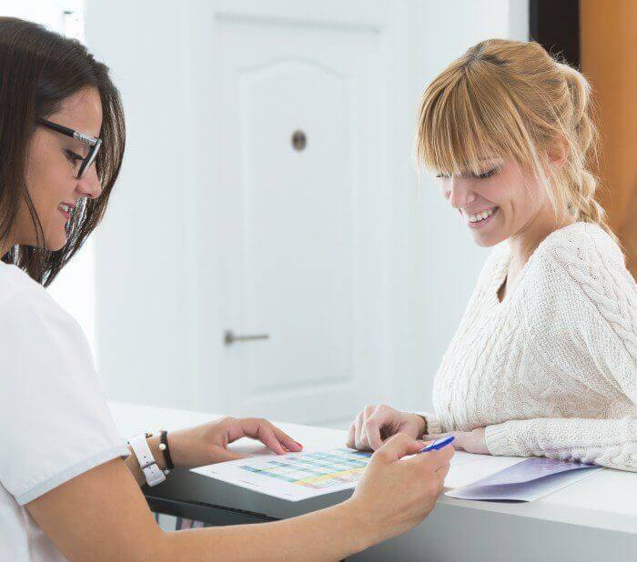 Team member helping patient at reception desk