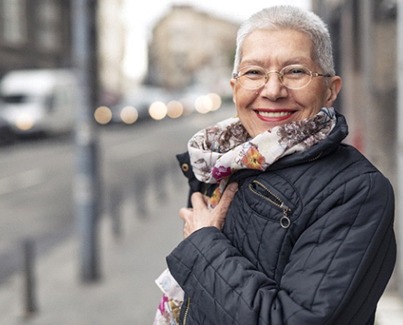 Woman on sidewalk smiling with dentures in Pewaukee