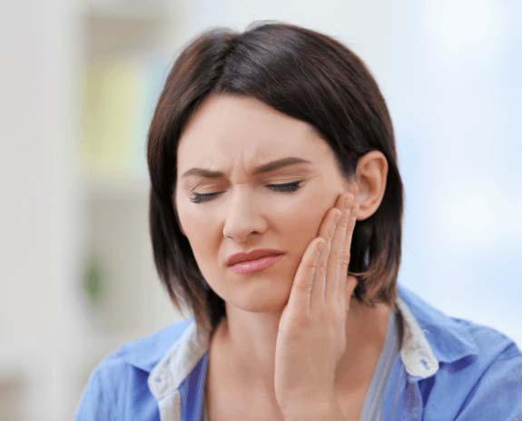 Woman in need of emergency dentistry holding jaw