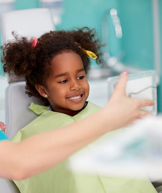 Little girl looking at smile after dental checkup visit