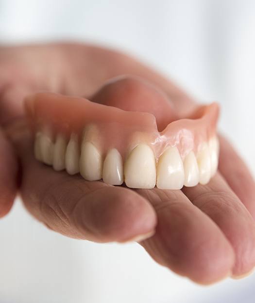 Hand holding a full denture