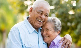 Man and woman smiling after replacing missing teeth