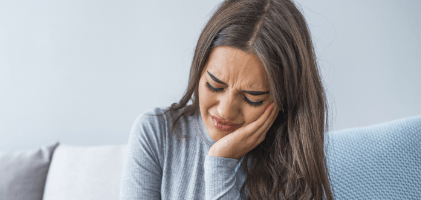 Woman in need of emergency dentistry holding jaw