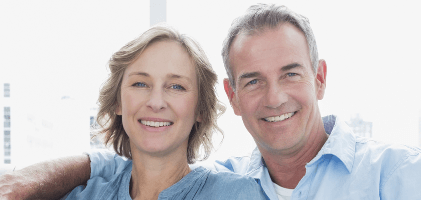 Man and woman smiling after replacing missing teeth