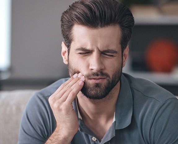 Man in need of tooth extraction holding jaw in pain